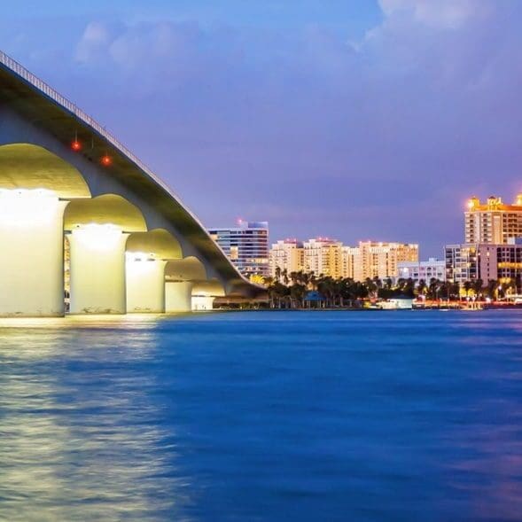 Illuminated waterfront bridge with city skyline
